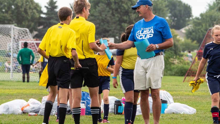Volunteer handing paper to referees at USA CUP