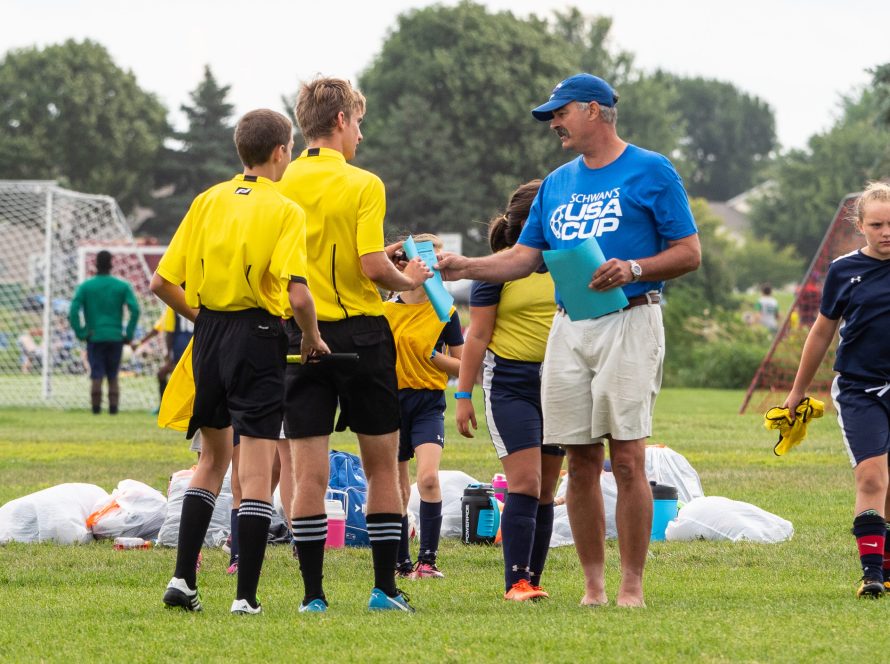 Volunteer handing paper to referees at USA CUP