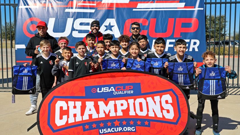 FC Atlas 11U boys holding up player bags in front of a champions sign.