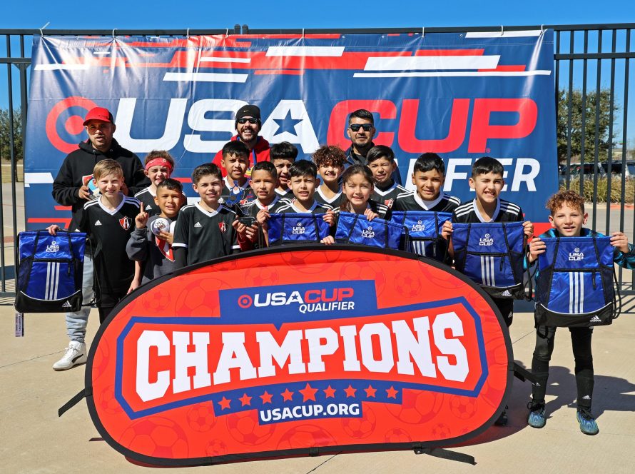 FC Atlas 11U boys holding up player bags in front of a champions sign.